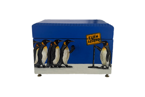 Houten antieke kist met Pinguins erop waarvan 1 pinguin een bord vasthoud met Turn around erop.